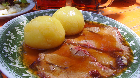 Traditionelles Gericht aus Böhmen auf Porzellantellern: Zwei Knödel mit Schweinebraten in 4 Scheiben