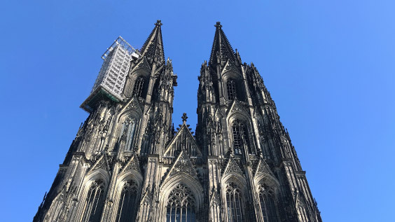 Radreise vorbei am Kölner Dom, blauer Himmel im Hintergrund