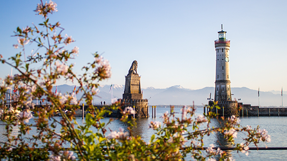 Blick auf die Türme der Hafeneinfahrt von Lindau mit Leuchtturm und Löwenskulptur