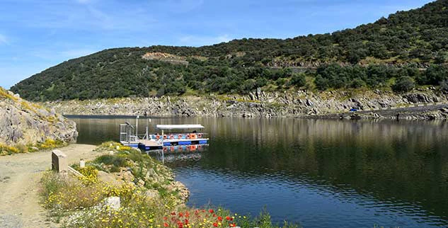 Bootsfahrt in der Extremadura mit waldigen Bergen im Hintergrund