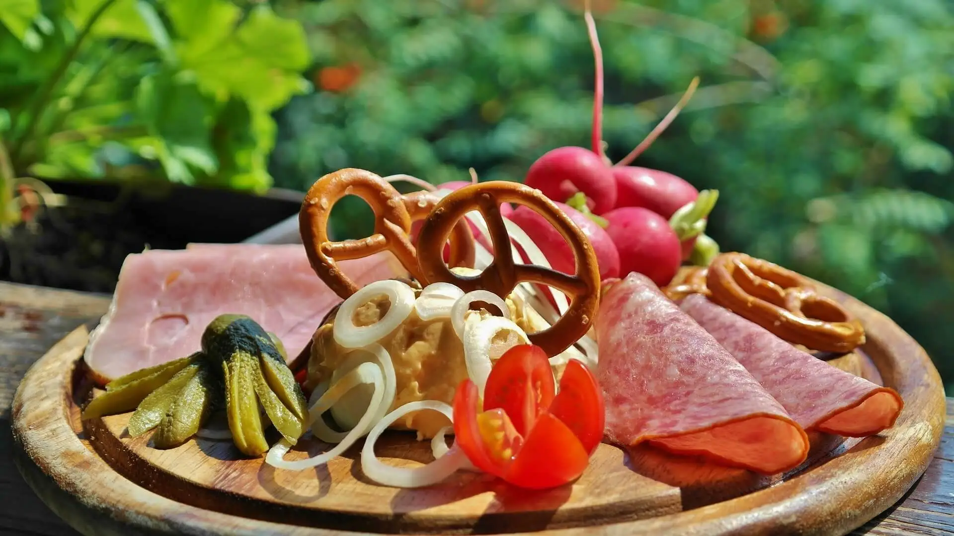 Belegtes brett mit Tomate, Brezeln, Zwiebeln, Schinken, Salami, Radischen