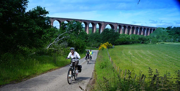 Radfahrergruppe bei dem Culloden-Viadukt, das längste gemauerte Eisenbahnviadukt Schottlands