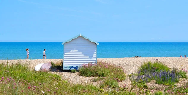 Weiße Strandhütte an einem Kieselstrand entlang der Radwege an der Küste Südenglands