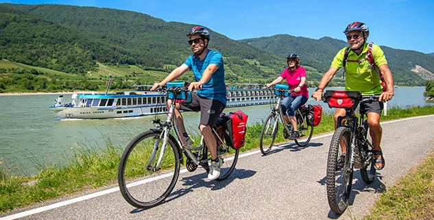 Radfahrer an der Donau, Schiff und Hügel im Hintergrund