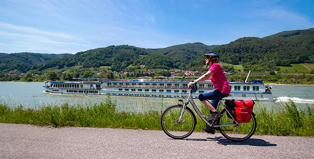 Radfahrerin der Landpartie entlang der Donau, Schiff im Hintergrund